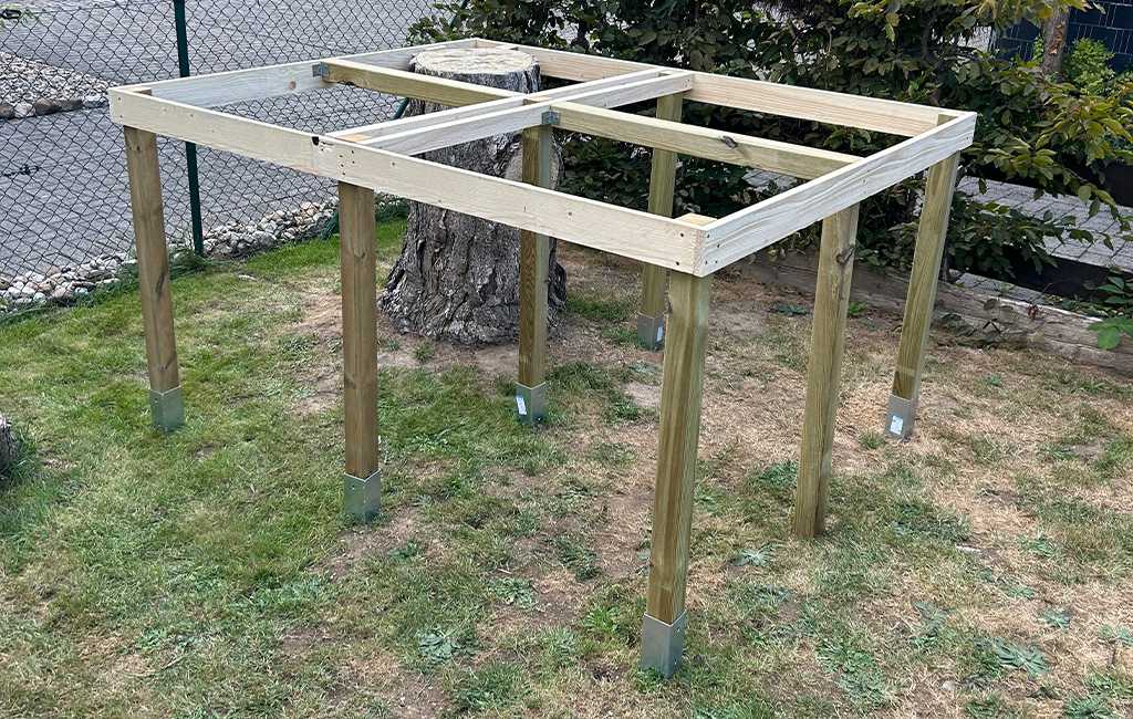 The wooden platform structure stands on eight posts, with a cut tree stump in the center.