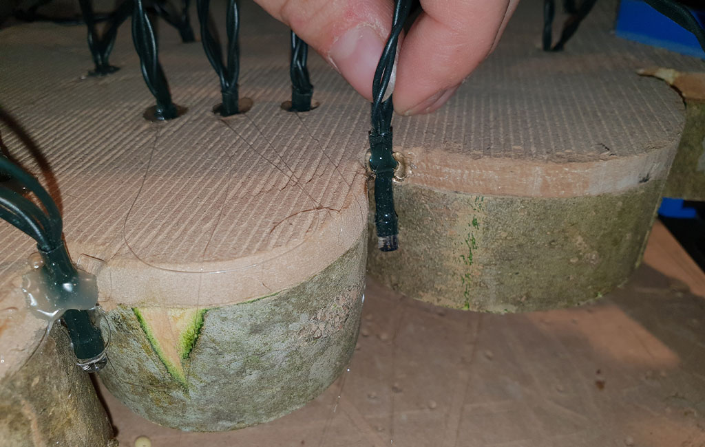 Close-up of string lights glued to the back of wooden discs with hot glue.
