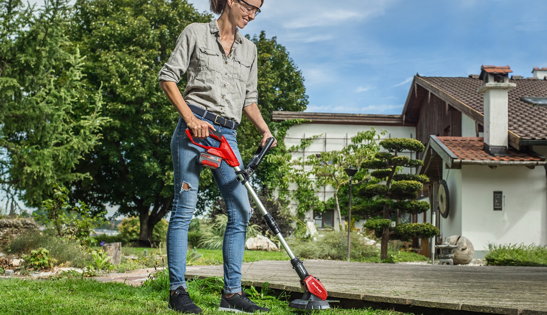 Woman trims the lawn under a footbridge