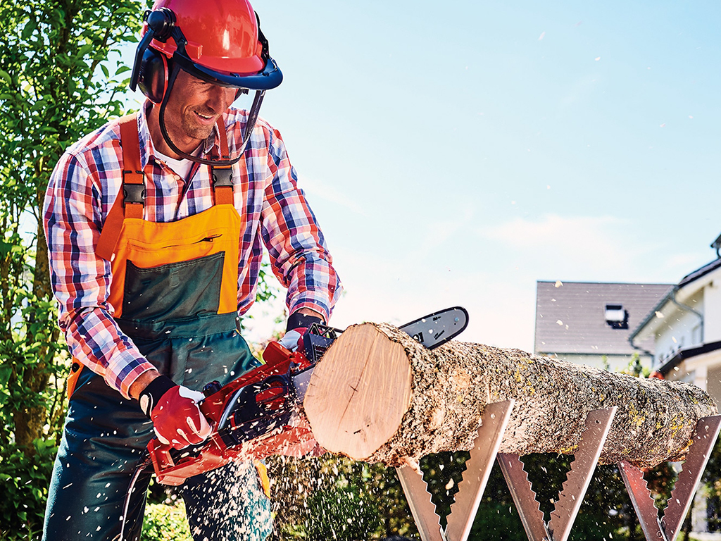 A man cuts a trunk with a chainsaw