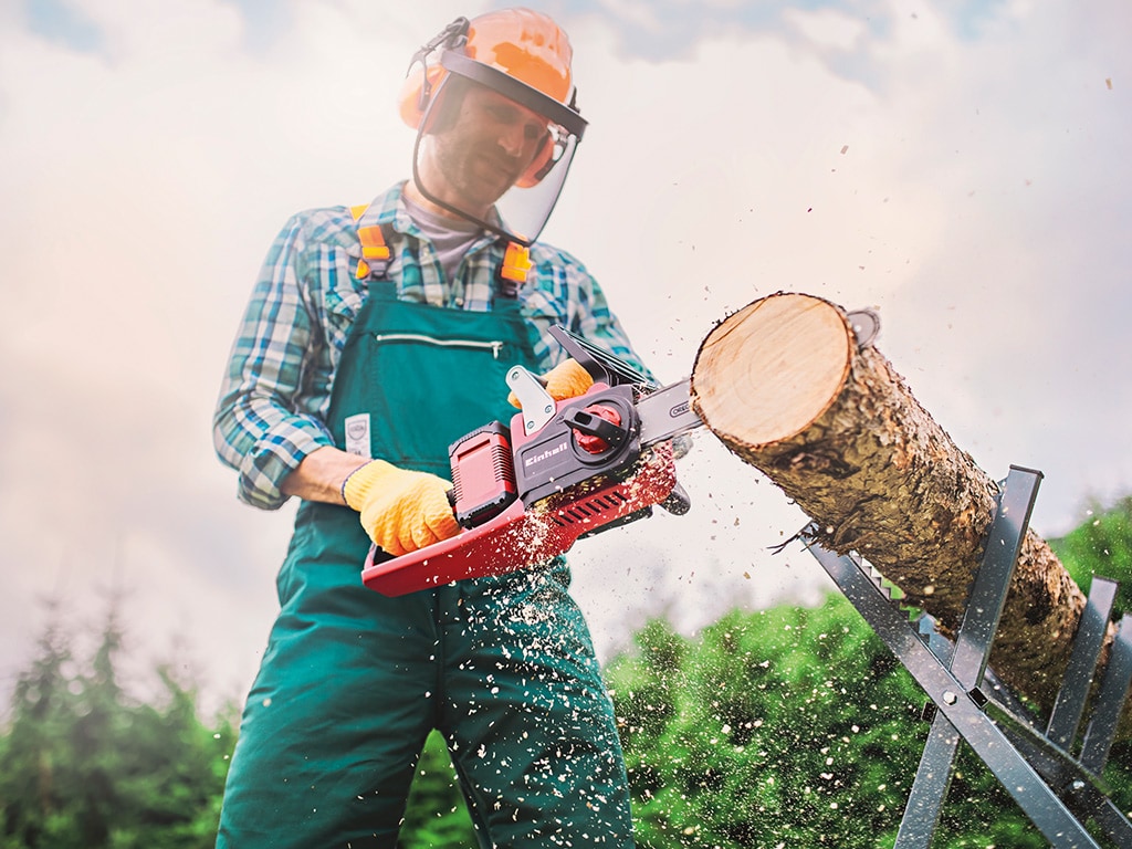 A man cuts a trunk with a chainsaw