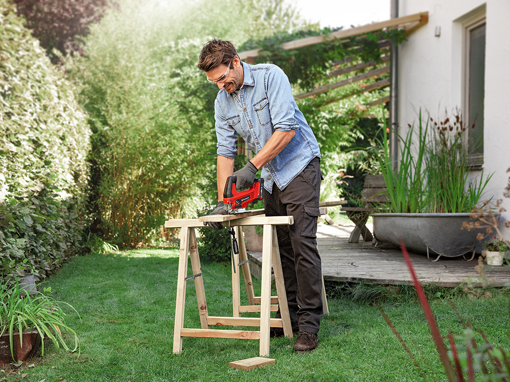 A man cuts a wooden board with a jigsaw