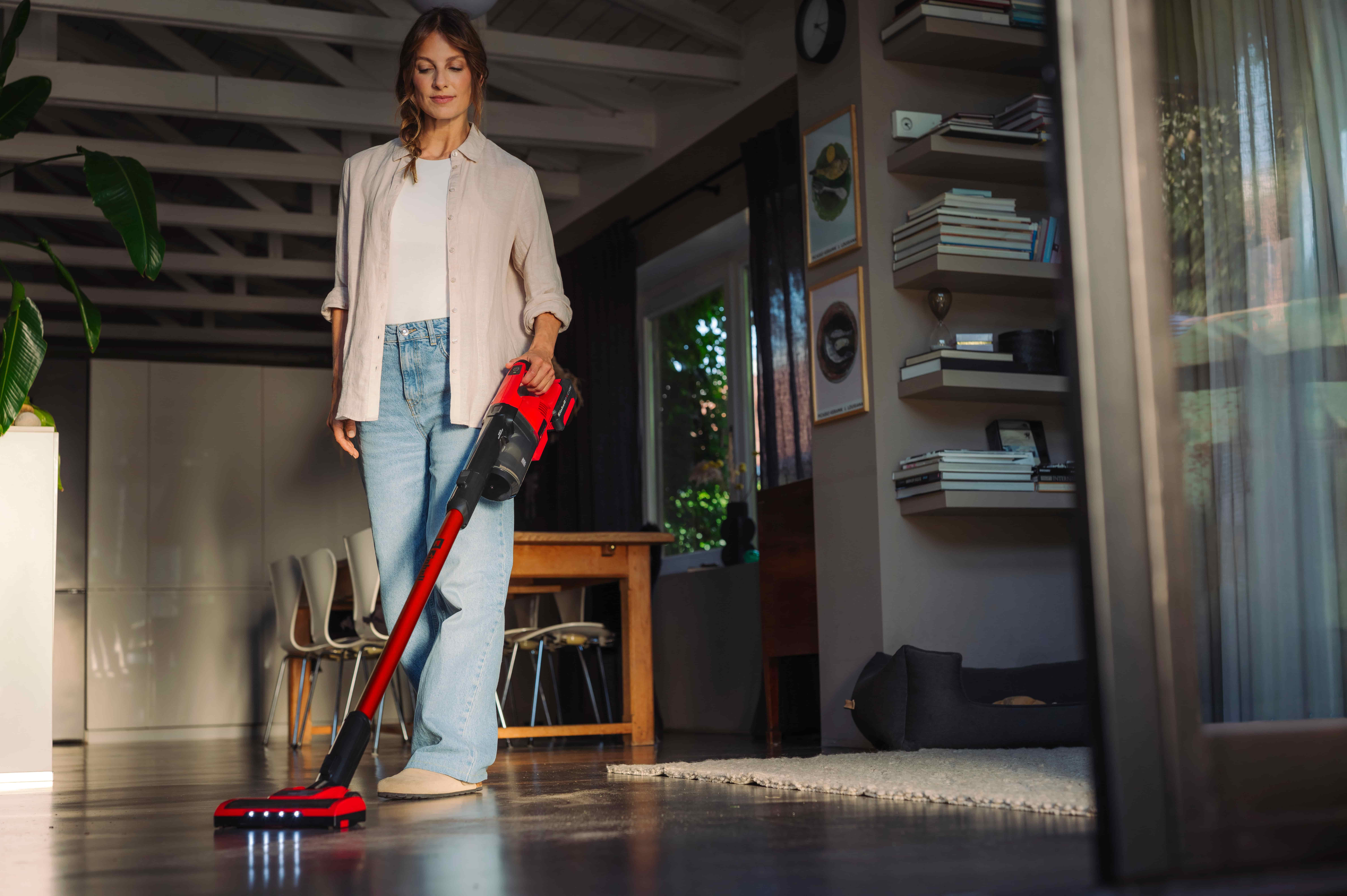 Person cleaning the floor at home with an Einhell cordless vacuum cleaner.