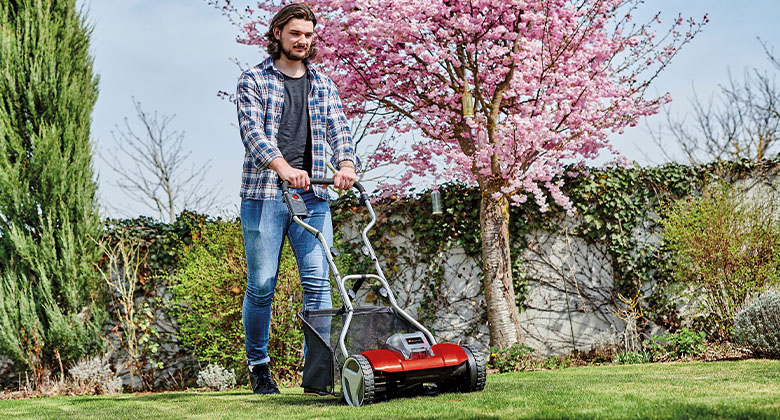 A man mowing the lawn with the hand lawn mower 