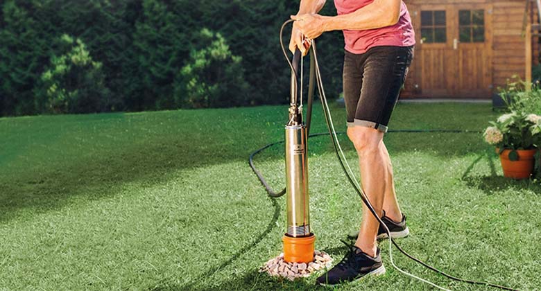 A deep well pump halfway into a narrow pipe.