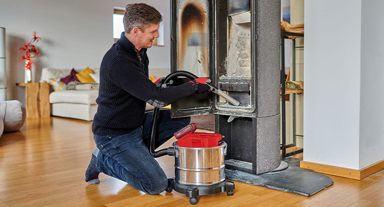 man cleanining an oven with an ash vacuum cleaner