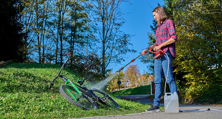 a woman is cleaning her bicycle with Einhell Cordless Pressure Washer